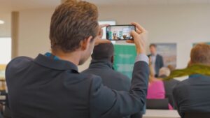 man taking a PICTURE WITH HIS PHONE OF AN EVENT